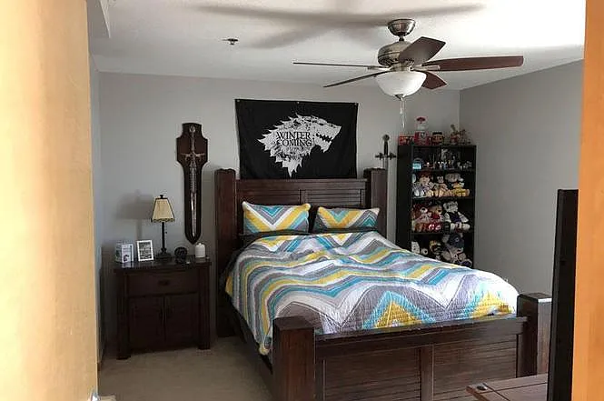 Spacious bedroom with ceiling fan and carpet floor.