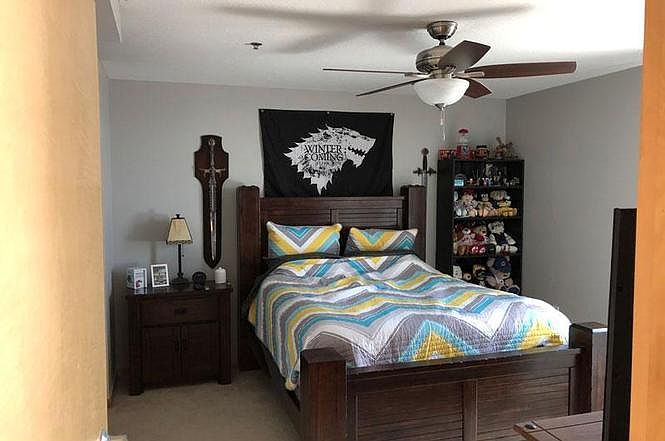 Spacious bedroom with ceiling fan and carpet floor.