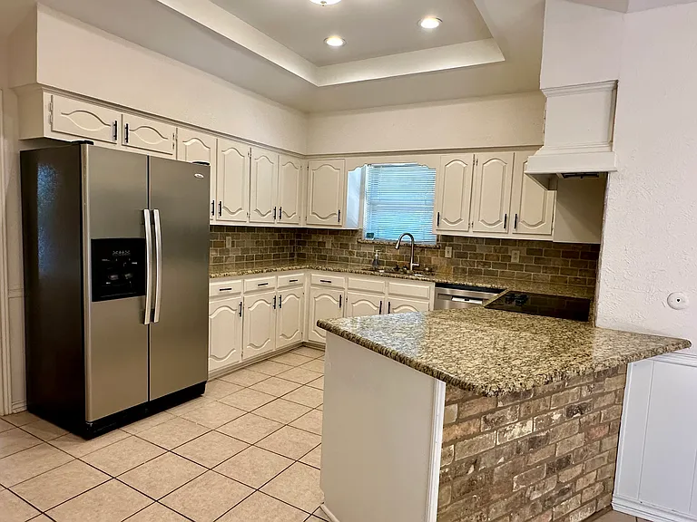 Kitchen with granite counters, decorative backsplash, a sink, light tile patterned floors, and stainless steel appliances
