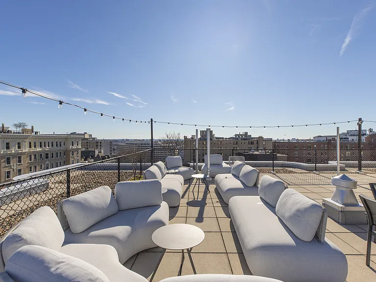 A rooftop patio with white couches and tables at 2100 Connecticut
