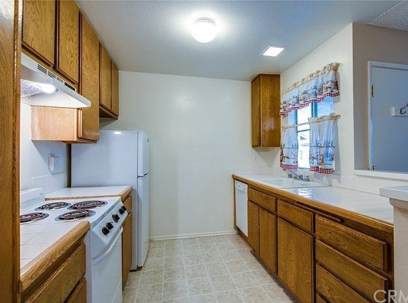 Kitchen has lots of cabinets, stove with fan, dishwasher, new refrigerator, disposal and window overlooking front entry.