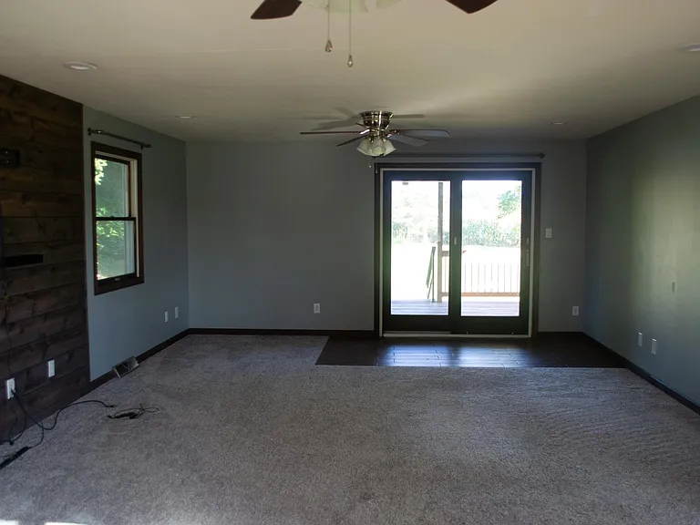 Living room with walk-out deck access and entertainment wall.
