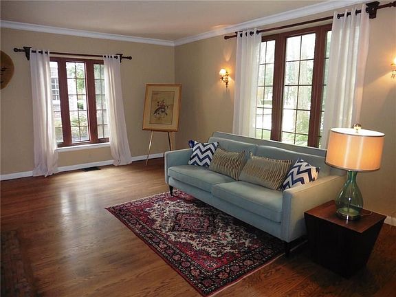 The living room features crown molding, hardwoods, and windows looking out to the beautiful front yard