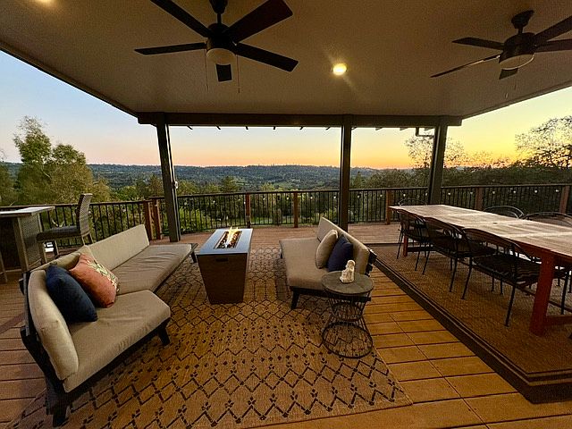 Large covered deck with stunning views, comfortable seating, firepit, and dining table.