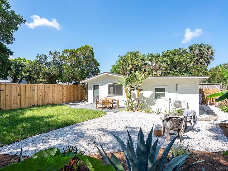 Freestanding guest house with private fenced yard, tropical landscaping, fire pit, and al fresco dining area