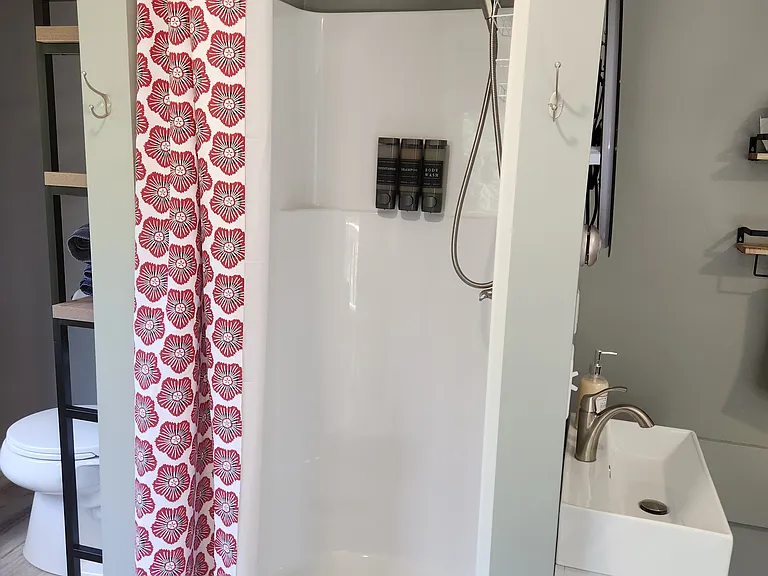 Bedroom 3 with queen bed on second floor, separate entrance, mini-fridge, mircowave, smart TV, fold away table and chairs, shower stall, bathroom sink, toilet, and views of backyard.