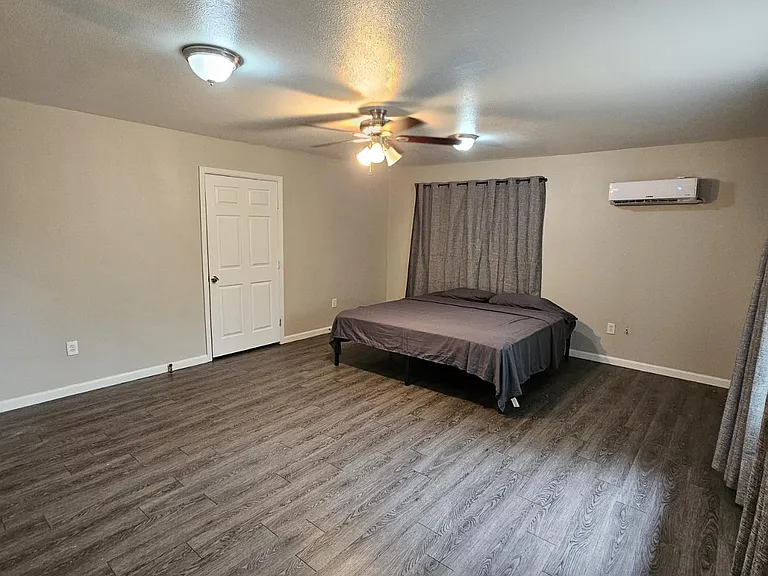 Spacious bedroom with durable wood-look flooring, ceiling fan lighting, and a mini-split A/C for year-round comfort.