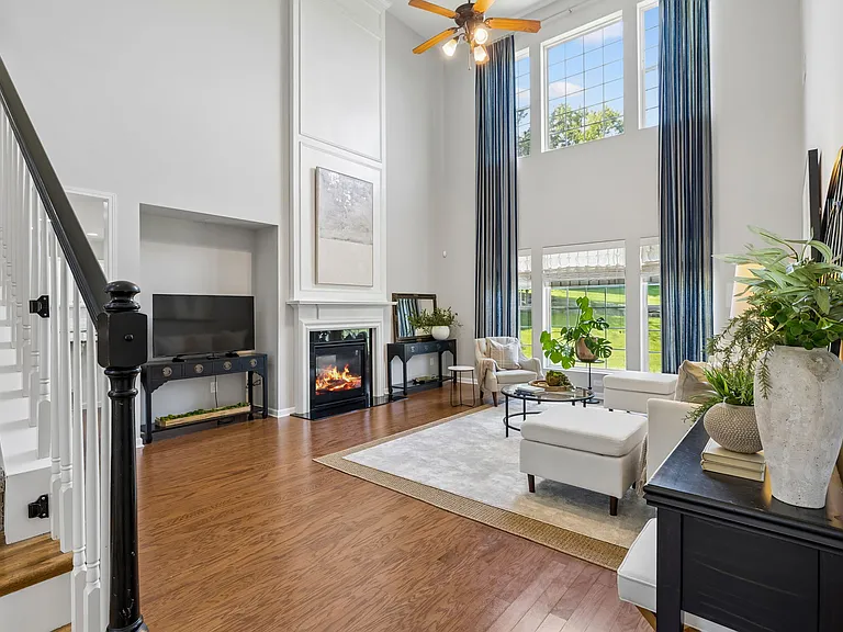 The impressive two-story great room is filled with natural light and features soaring ceilings, expansive windows, and a striking double-sided fireplace that serves as the focal point of this elegant gathering space.