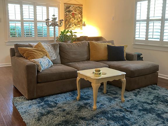 Living Room with comfy Crate and Barrel couch. Just behind is a spacious work station featuring a drafting table desk.