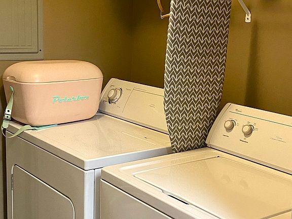 The laundry room has shelving for supplies. Tile floor.