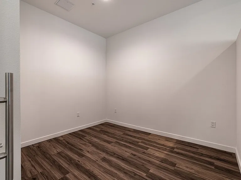 Spacious bedroom with hardwood floor in Live and Work apartment at 1400 FIG Apartments in Los Angeles, California.