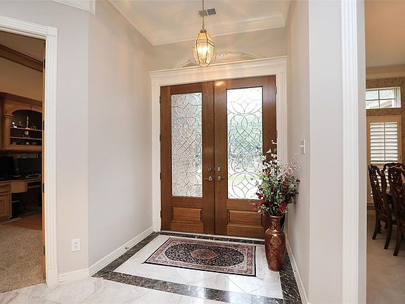 The entry foyer features marble tile, which also extends into the formal living room. To the left in the photo is the private study and to the right is the formal dining room where you will entertain family or guests.