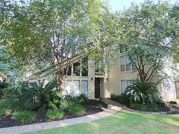 The curved sidewalk guides you to the front door, across the mature landscaping in the front yard.