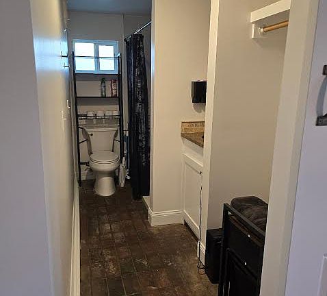 Toilet, bathroom, shower, vanity and open closet with brick pavers