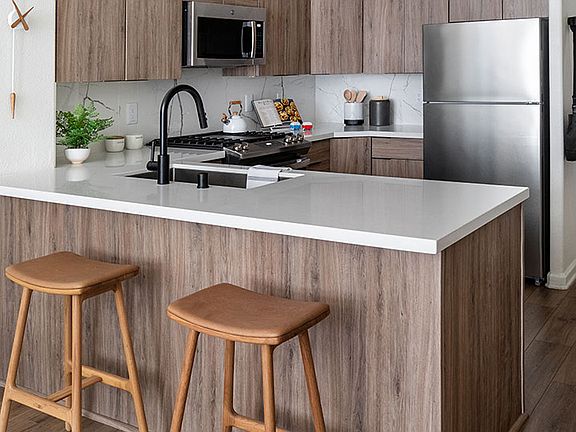 Apartment Kitchen with Stainless Steel Appliances, quartz counters and wood floors.