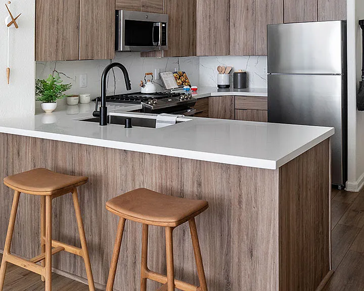 Apartment Kitchen with Stainless Steel Appliances, quartz counters and wood floors.