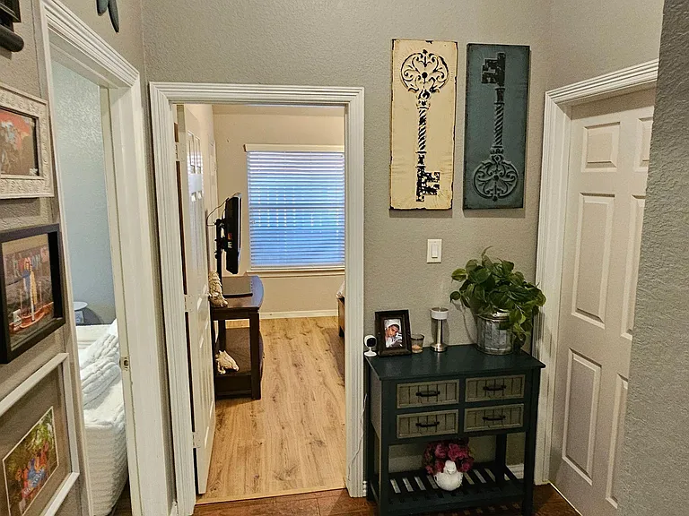Welcoming hallway with wood-look flooring, neutral walls, and convenient access to nearby rooms and storage.