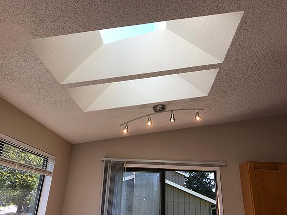 Natural skylights and new light fixtures and blinds in dining area. Patio sliding door leads you to the huge backyard