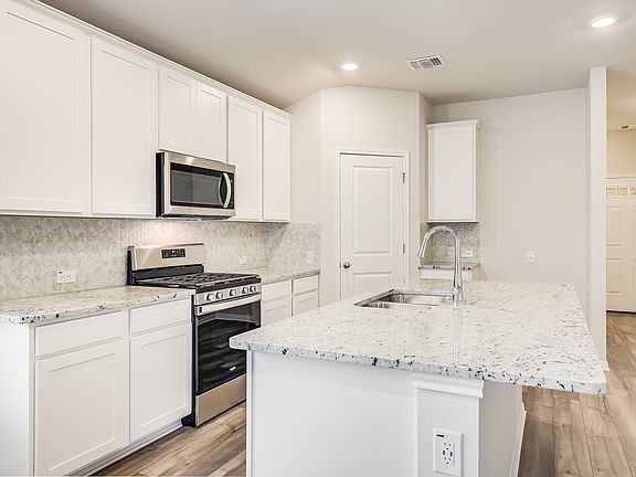 This kitchen features linen-colored cabinets and granite countertops.