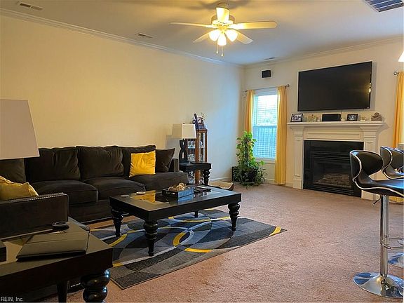 Living area with center light, ceiling fan and crown moulding.