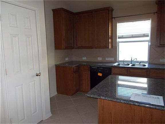 View of Kitchen with granite countertop & tile splashback.