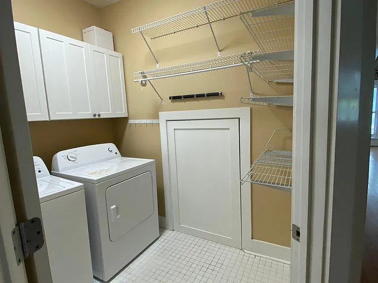 Laundry room, washer dryer, shelves, cabinets, tile floor.