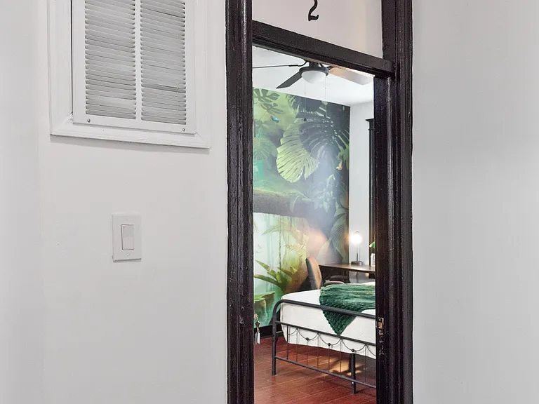 Private bedroom with hardwood-style floors, ceiling fan, and space for a bed and desk in a quiet interior setting.