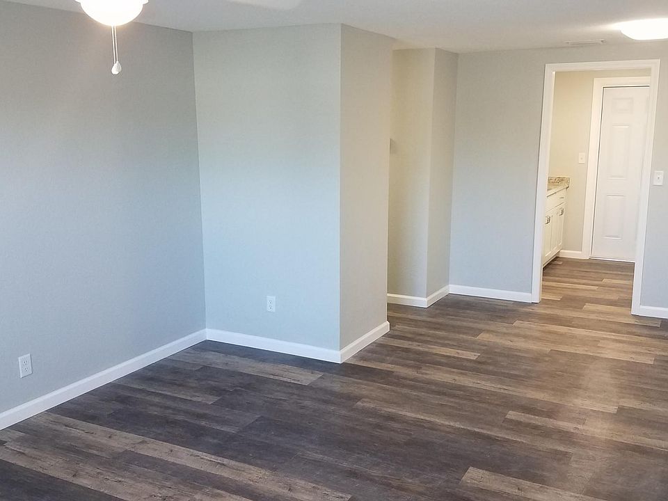 View of living room, dining nook and leading into kitchen. New light fixtures throughout and ceiling fan in living room. Beautiful wood grain vinyl plank floors throughout.