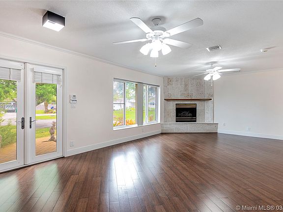 Front living room (unstaged) with corner rock faced gas fireplace and bamboo wood floors. Custom impact doors and windows through out house.