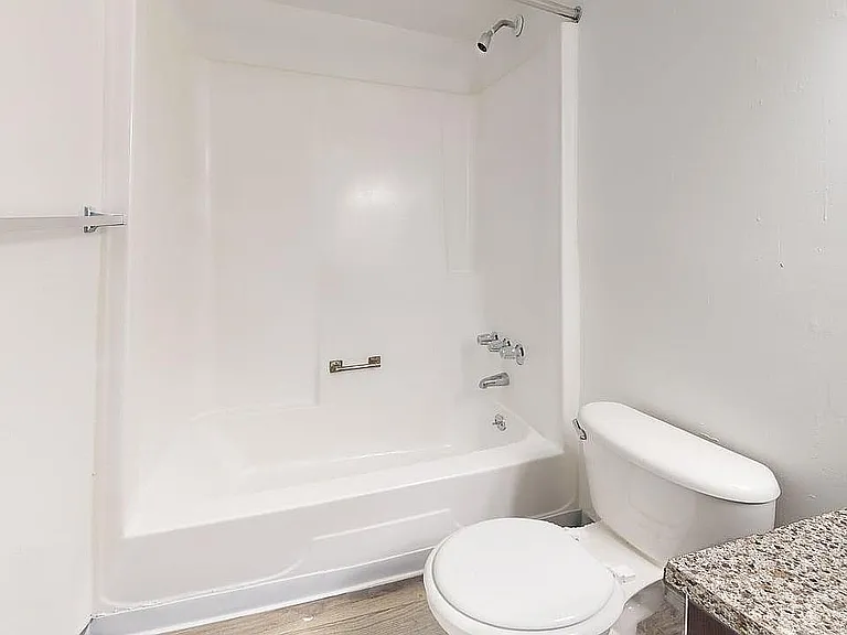 Modern bathroom with sleek white bathtub, elegant granite countertop, and polished fixtures.