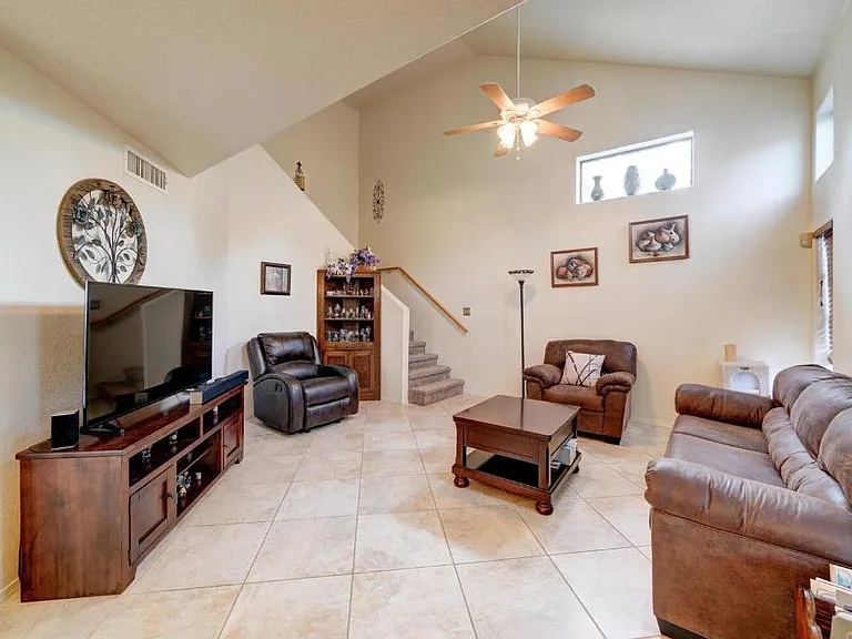 Living room has lots of space with open airy feel and new ceiling fan in July 2026 (old fan in picture).