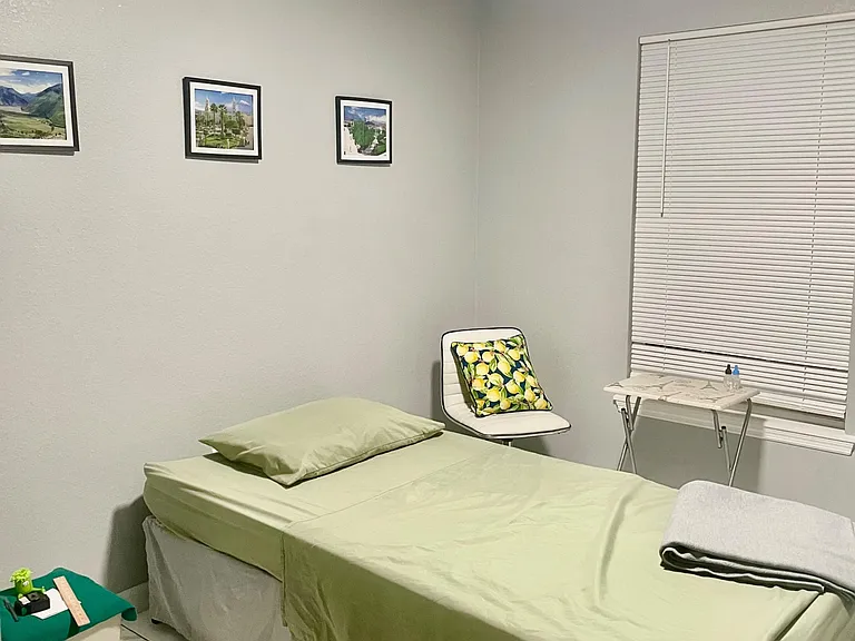 Furnished bedroom with a twin bed, tiled flooring, wall art, and a window with blinds plus a small desk surface.