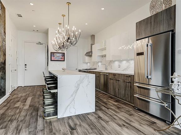 The stunning kitchen features an eat-in Dekton waterfall island that seats at least 5 people, upgraded chandelier lighting fixtures and island storage.