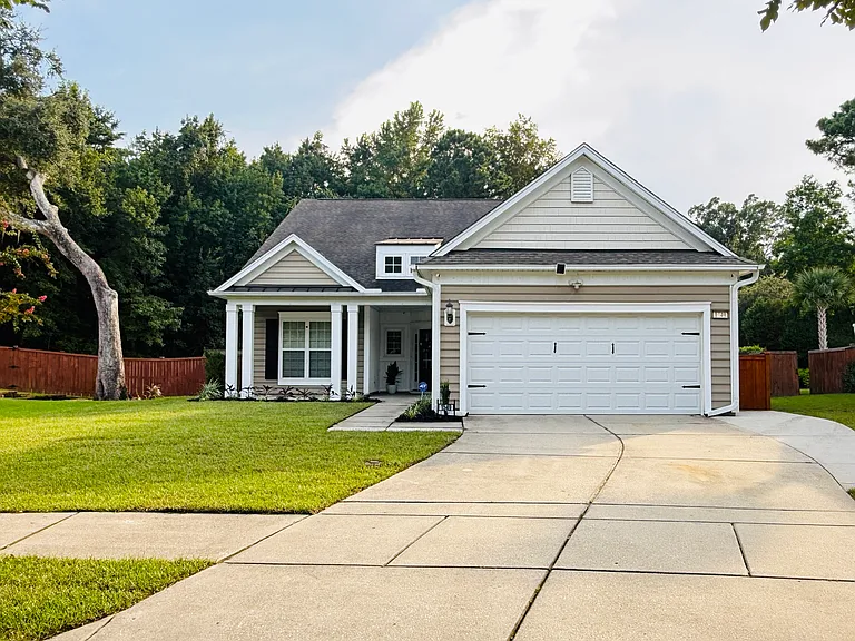 Stunning single-family rental with an expansive driveway, attached garage, and private fenced yard nestled against a serene wooded backdrop."