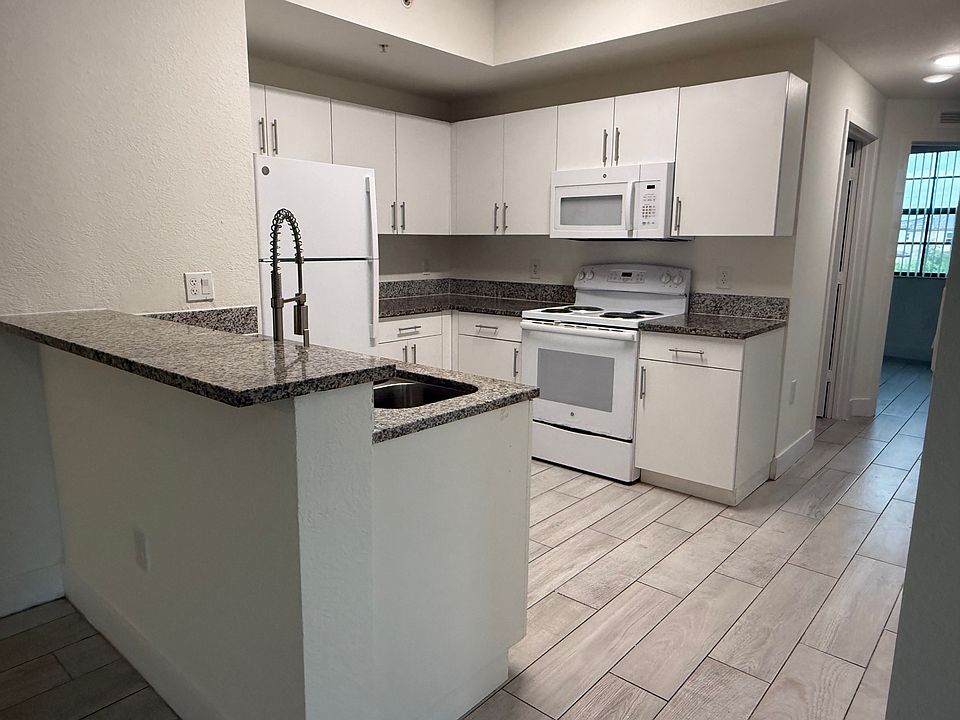 Spacious modern kitchen featuring granite countertops, sleek white cabinetry, and plenty of storage space.