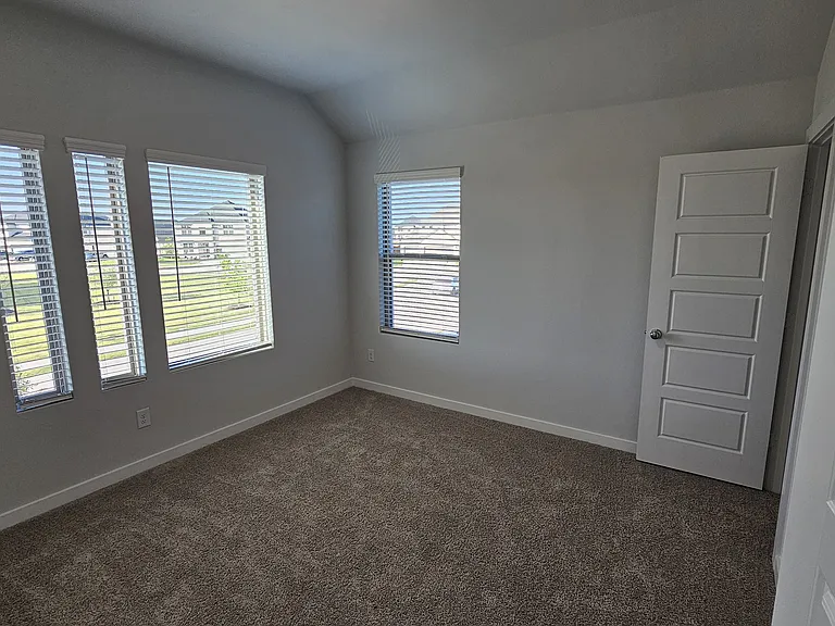 Sun-filled upstairs bedroom featuring large windows with a direct, scenic view of the community park