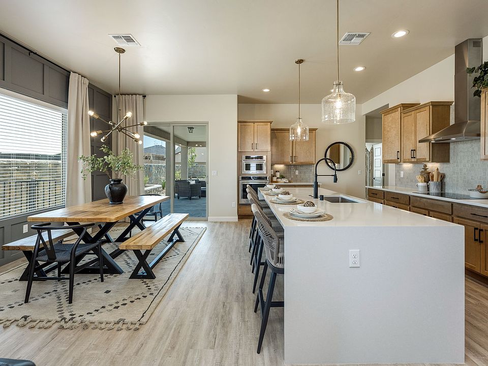 Modern open kitchen and dining area with wood cabinets, white island with bar stools, pendant lights