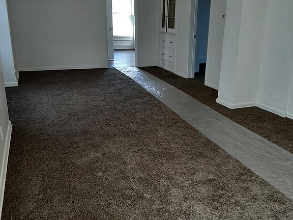 View from living /dining room, looking toward kitchen and china cabinet at back, with bedrooms off to the right side of picture (plastic is temporary carpet protection)