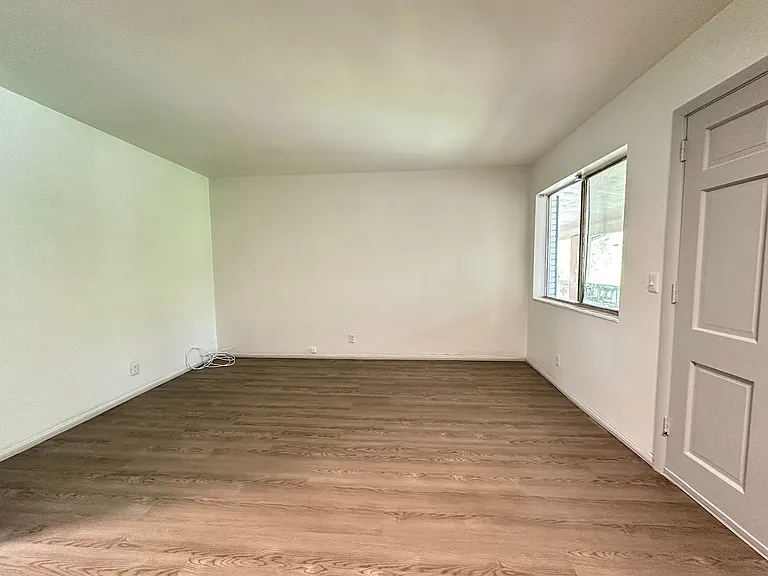 Bright, airy living room with elegant wood flooring and large window offering natural light.