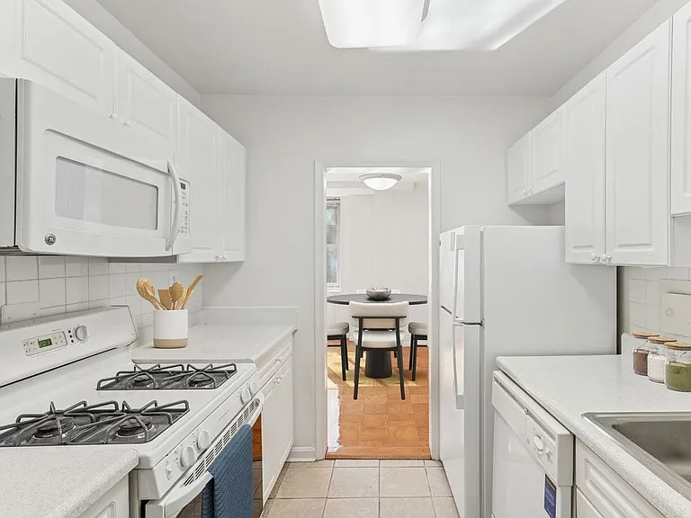 Kitchen with white cabinetry, white laminate countertops, white tile backsplash, white appliances, and hard surface flooring