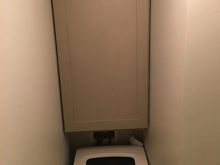 Washing machine with storage cabinet in laundry room