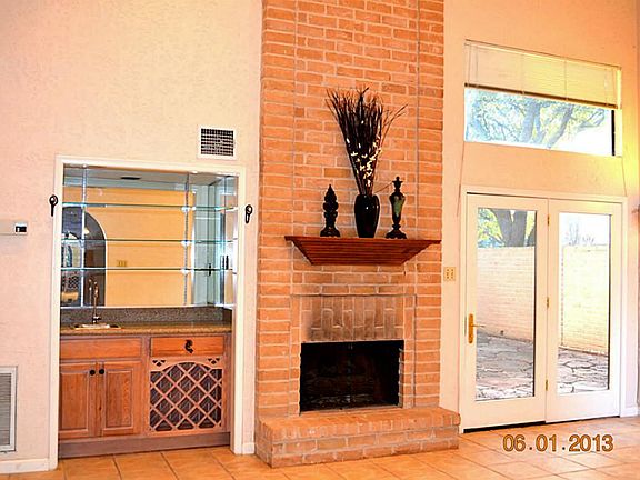 Spacious Den with bar, soaring ceilings, and inviting fireplace.  French Doors lead to patio area.