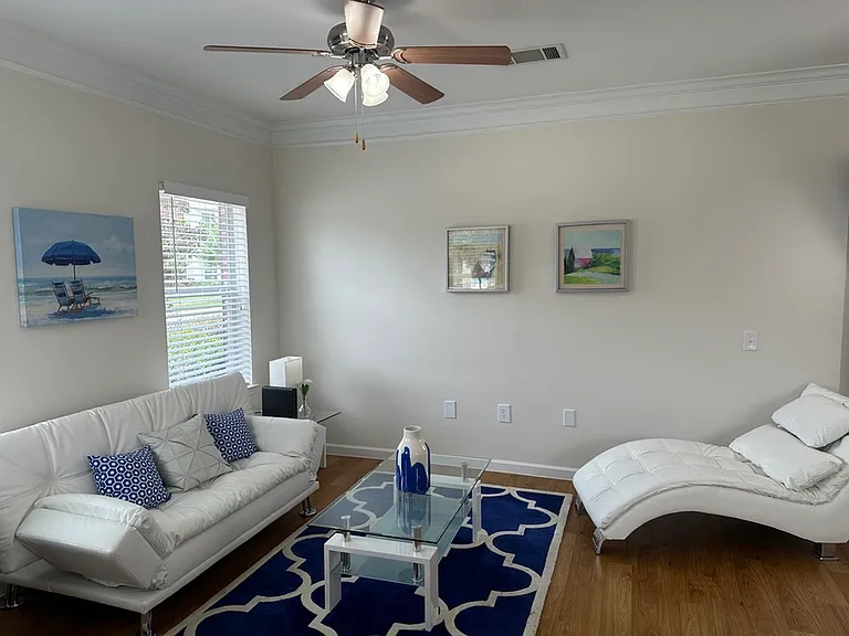Elegant living room with white modern furniture, artistic wall decor, and a cozy blue accent rug. Elegant living room with white modern furniture, artistic wall decor, and a cozy blue accent rug.