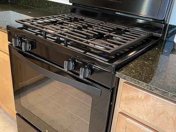 Brand new gas range and stove, cabinets, and granite countertops.