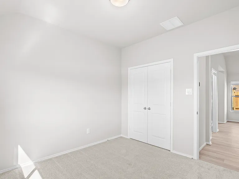 Carpeted secondary bedroom with double door closet, open to hallway a?? bright and move-in ready.