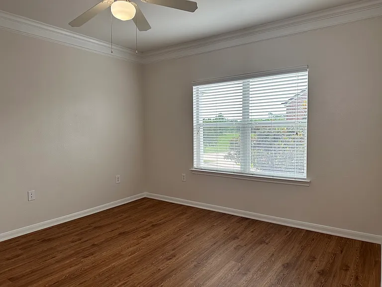 Bright and spacious room with large window, elegant wood-style flooring, and ceiling fan, perfect for versatile living. Bright and spacious room with large window, elegant wood-style flooring, and ceiling fan, perfect for versatile living.