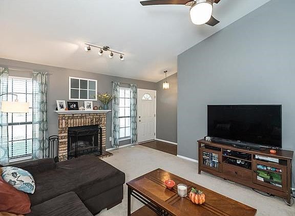 Vaulted Living Room with ceiling fan and woodburning fireplace.