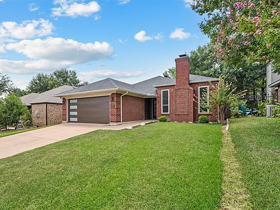 Brick exterior with a prominent brick chimney, attached garage with a modern door, and a concrete driveway