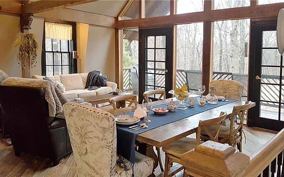 Great Room with wall of windows looks out to spectacular views and opens to covered deck.  Exposed beams, vaulted ceiling, antique millwork, newel posts and railings, and sculpted head corbels complete this rustic look