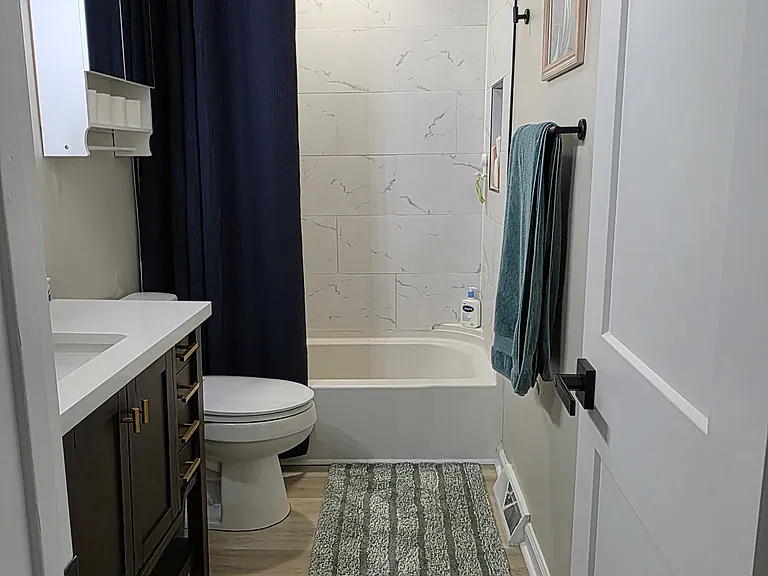 The recently updated bathroom features a bathtub and shower, along with plenty of storage spaces.